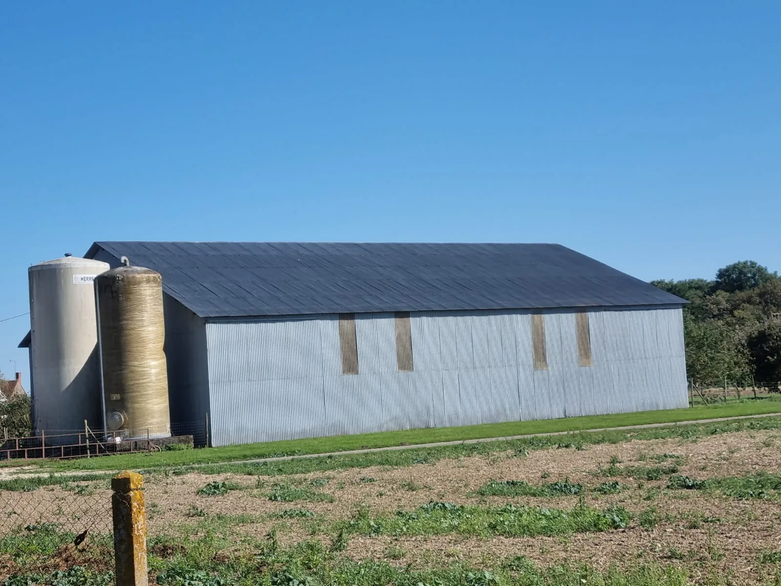 Bâtiment agricole avec silos et toiture repeinte