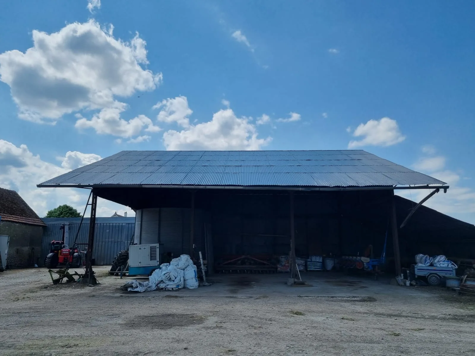 Hangar agricole ouvert abritant le matériel de l'exploitation