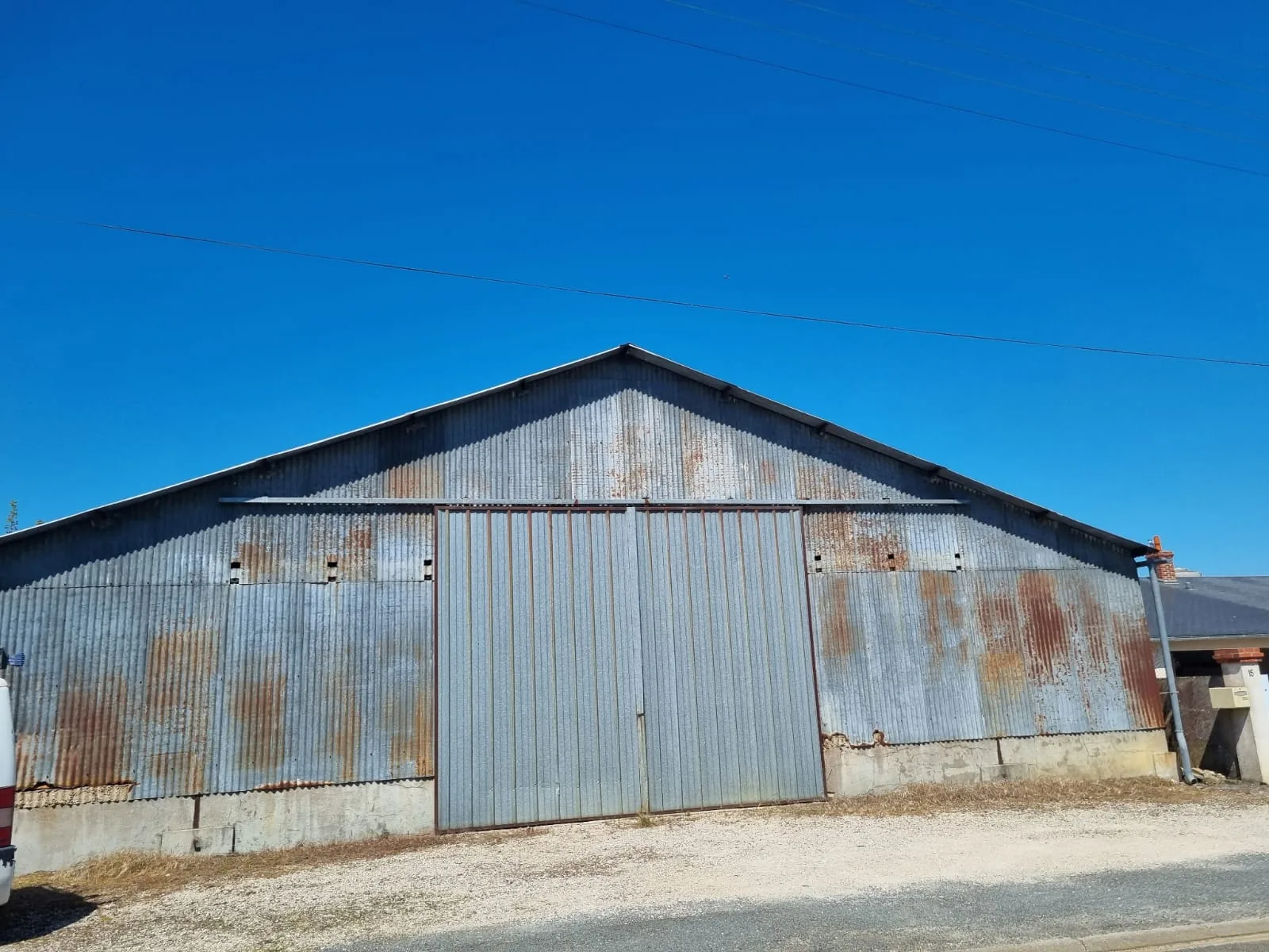 Avant — Hangar agricole en tôle ondulée nettoyé et repeint en gris